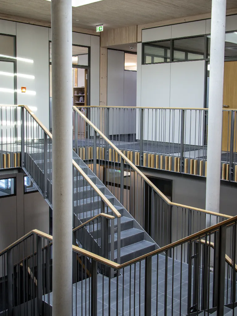 Treppenatrium mit Treppenwangenbekleidung. Geländer mit Holzhandlauf.